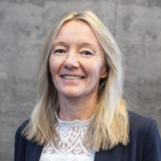 Portrait von Ute Pfister vor einem grauem Hintergrund.